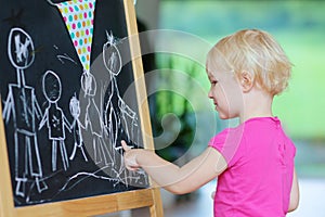 Toddler girl drawing on black board