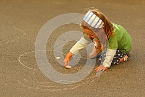 Toddler girl drawing with chalk on asphalt
