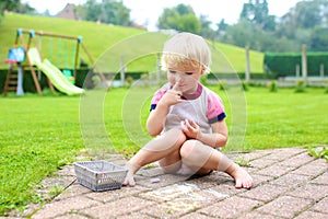 Toddler girl drawing with chalk outdoors