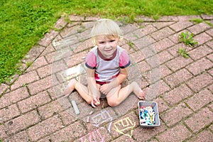 Toddler girl drawing with chalk outdoors