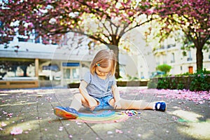 Toddler girl drawing rainbow with colorful chalks