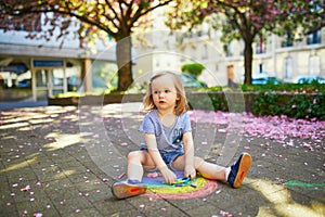 Toddler girl drawing rainbow with colorful chalks