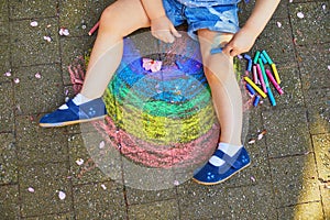 Toddler girl drawing rainbow with colorful chalks
