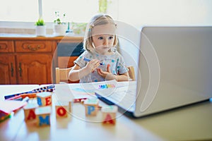 Toddler girl drawing rainbow in front of laptop