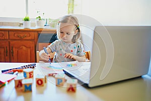 Toddler girl drawing rainbow in front of laptop