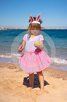 Toddler girl with easter eggs on the beach