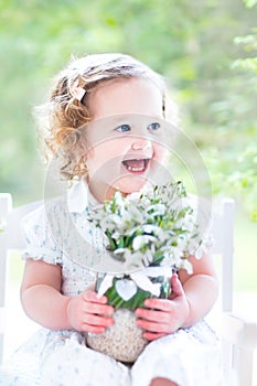 Toddler girl with first spring flowers in crystal vase