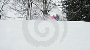 Toddler girl going down a sledge on a snowy hill