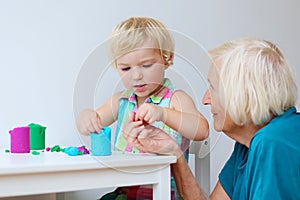 Toddler girl with grandmother creating from plasticine