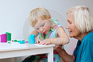 Toddler girl with grandmother creating from plasticine