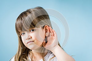 Toddler girl with hearing problem on light blue background. Close up, copy space