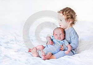 Toddler girl holding her newborn baby brother