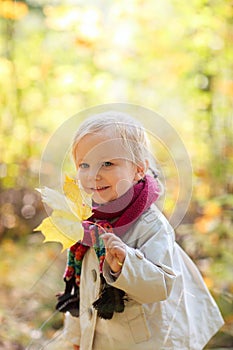 Toddler girl holding yellow leaf