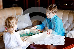 Toddler girl and kid boy playing table soccer with family at home. Smiling children, siblings play board football