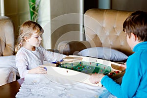 Toddler girl and kid boy playing table soccer with family at home. Smiling children, siblings play board football