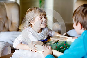 Toddler girl and kid boy playing table soccer with family at home. Smiling children, siblings play board football