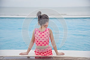 Toddler girl Kid swim playful in swimming pool summer time with pink swimwear in blue water at hotel swimming pool outdoor. Happy