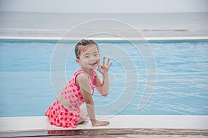 Toddler girl Kid swim playful in swimming pool summer time with pink swimwear in blue water at hotel swimming pool outdoor. Happy