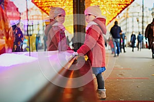 Toddler girl looking at window glass of large department store decorated for Christmas