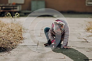 Toddler girl painted on the asphalt with a chalk, outdoor
