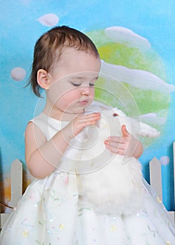 Toddler girl petting bunny at easter