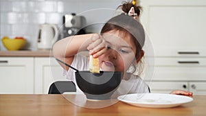 toddler girl picky eater at home kitchen. learning o eat with spoon. bad table manners of kid
