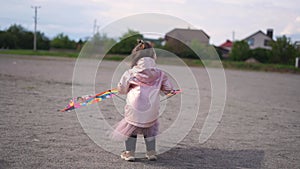 Toddler girl in pink tutu dress playing with kite. Spring outdoors activity