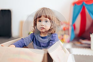 Toddler Girl Playing in a Cardboard Box at Home