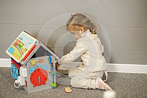 Toddler Girl Playing with Learning Toy House. Busy board