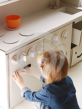 Toddler girl playing with toy kitchen at home