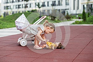 Toddler girl playing with toy stroller with doll. Two years old. Developmental milestones