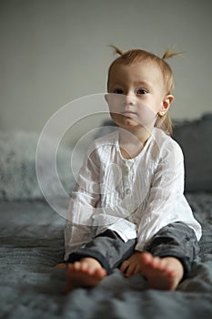 Toddler girl sits on the bed