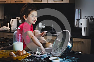 Toddler girl smiling while grab chocolate in a mesy table photo