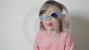 Toddler girl with swimming googles at home. Summertime kids activity.