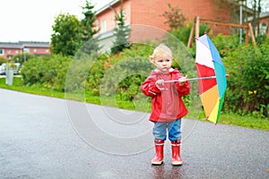 Toddler girl with umbrella outside on rainy day