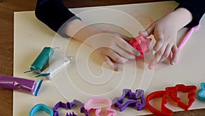 Toddler hands playing colorful play dough with plastic molds