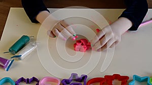 Toddler hands playing colorful play dough with plastic molds of various shapes