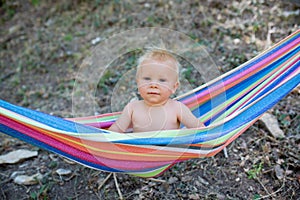 Toddler Happy child boy lying in a hammock in garden. Summer holidays concept. Child is resting in nature. Cute kid enjoy summer