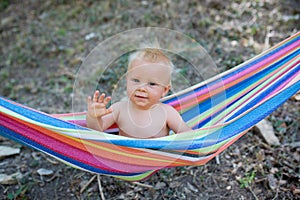 Toddler Happy child boy lying in a hammock in garden. Summer holidays concept. Child is resting in nature. Cute kid enjoy summer