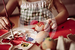 Toddler having fun painting Easter eggs.