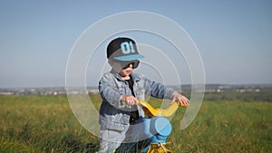 Toddler kid in funny glasses biking. Helping to ride a bike. Learning to ride a bike concept.