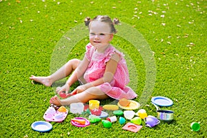 Toddler kid girl playing with food toys sitting in turf