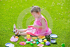 Toddler kid girl playing with food toys sitting in turf