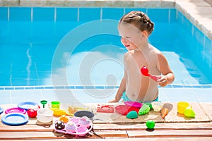 Toddler kid girl playing food toys in swimming pool