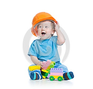 Toddler kid in hardhat plays with toy blocks over white background