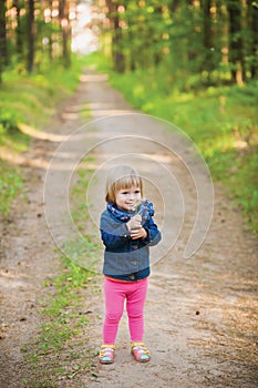 Toddler laughing girl in forest with flowers