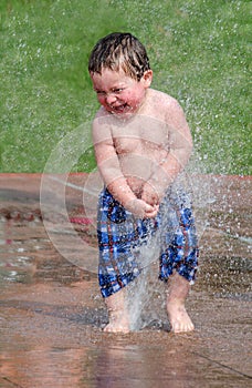 Toddler laughing in a summer fountain photo