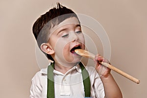 Toddler licking wooden spoon