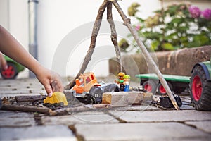 Toddler playing with construction toys in the backyard on a blurred background