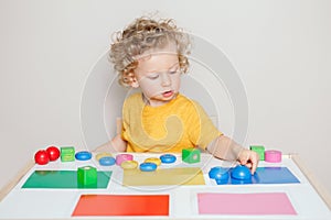 Toddler playing with learning toys at home or kindergarten. Baby sorting organising objects blocks with specific color. Early age